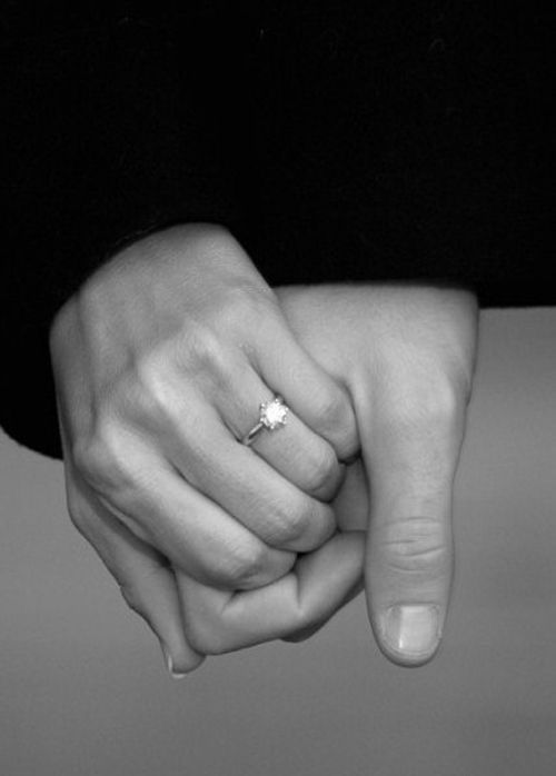 Dos manos entrelazadas con un anillo de compromiso
